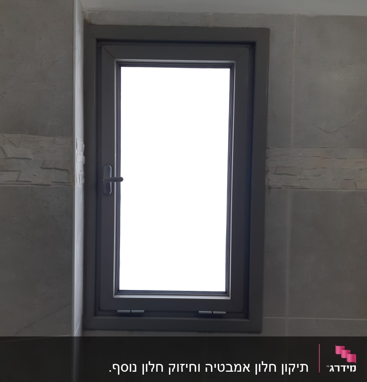 חלון אלומיניום עם מסגרת אפורה על קיר אריחים